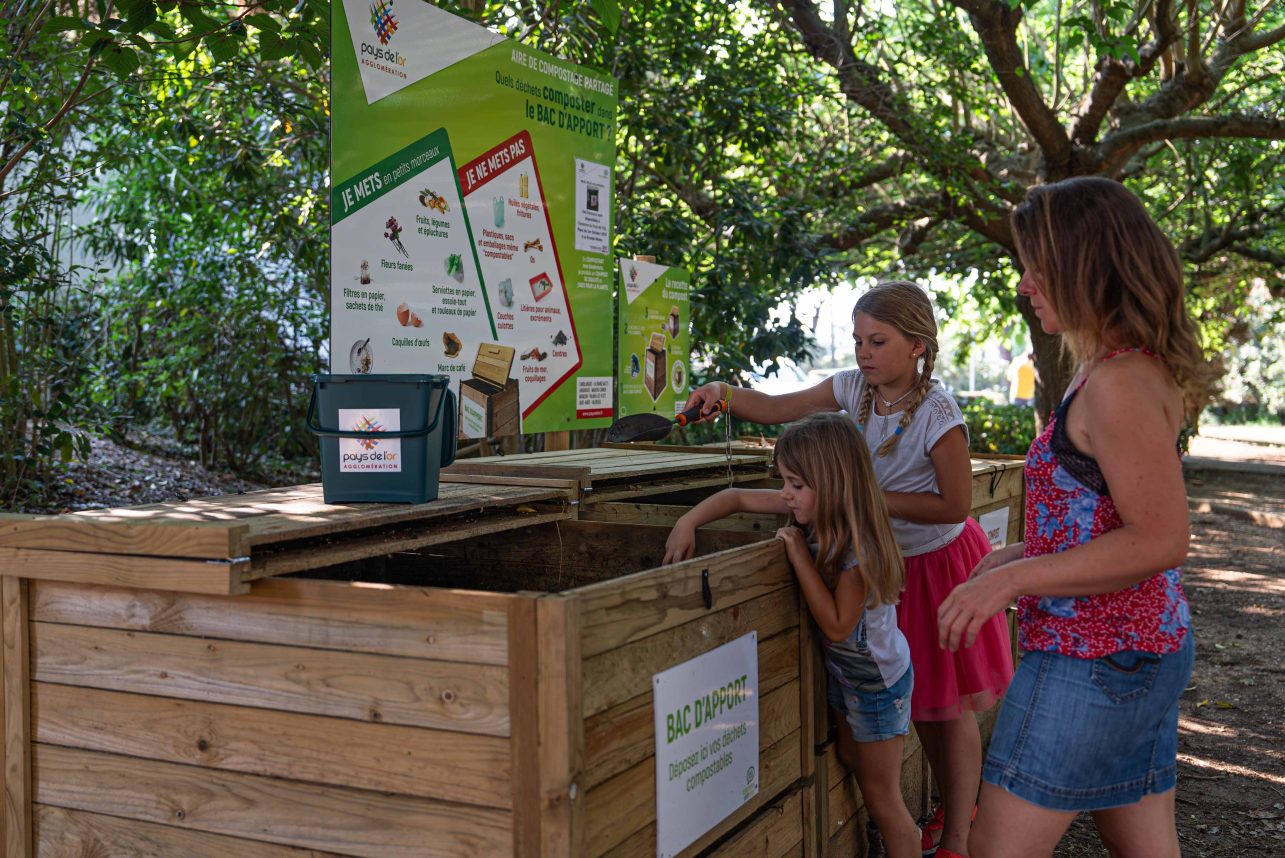 Deux filles et une femme en train d'utiliser l'aire de compostage partagé