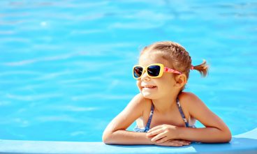Une petite fille souriante dans une piscine.