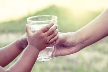 Femme donnant un verre d'eau à un enfant